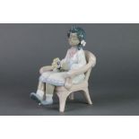 A Lladro figure of a young girl sitting in a wicker chair holding a bouquet. 5699 6 1/2"The figure