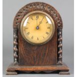 A 1930's bedroom timepiece with paper dial and Roman numerals contained in a carved oak arch