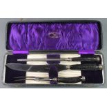 An Edwardian cased horn handled carving set with plated terminals