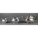 A silver plated 3 piece tea set with demi-fluted decoration, gadroon and shell rims with ebony