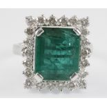 An 18ct white gold rectangular emerald and diamond ring, the central emerald 9.3ct surrounded by