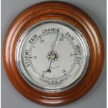 A 1930's aneroid barometer with silvered dial contained in a turned mahogany surround 7"