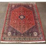 A Persian Abadeh rug with red and blue ground and diamond medallion to the centre 100" x 72"