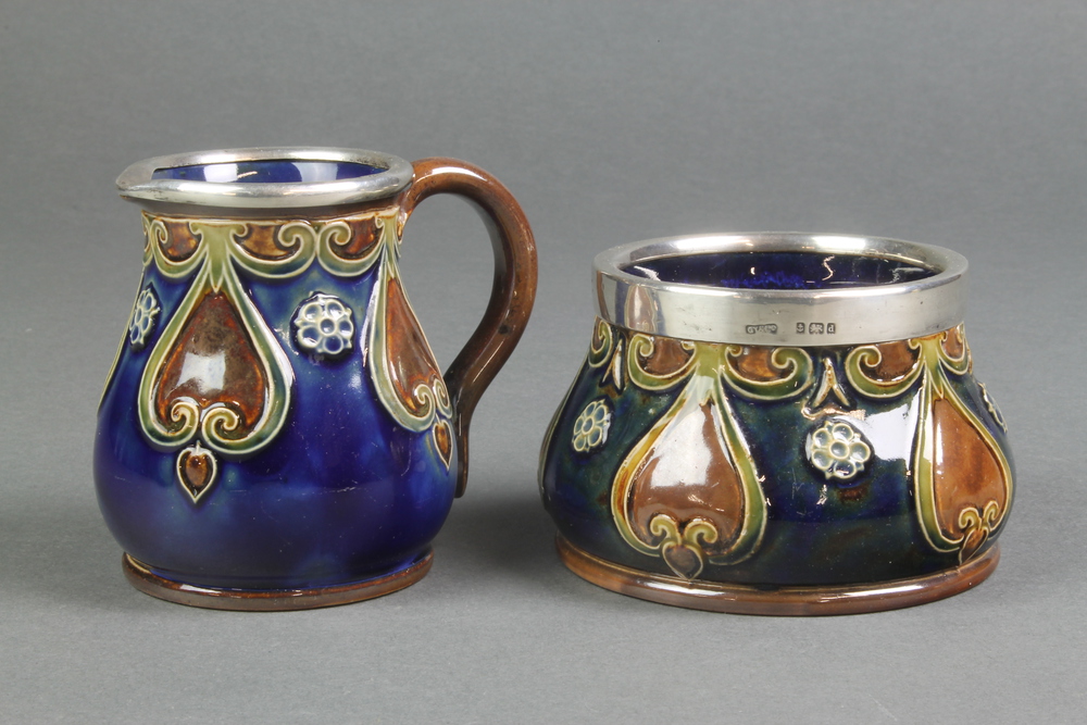 A Royal Doulton blue ground jug with geometric decoration having a silver lip, a matching sugar bowl