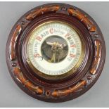 An Edwardian aneroid barometer with enamelled dial contained in a carved mahogany roundell case 8"