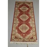 A red ground Persian style Belgian cotton runner with 3 medallions to the centre 82" x 27"