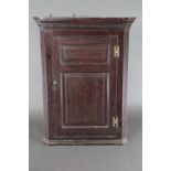 A mahogany corner cabinet with moulded and dentil cornice, fitted shelves enclosed by panelled doors