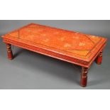 A rectangular Indian hardwood painted table with red ground and floral decoration on turned supports