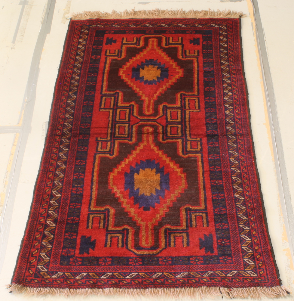 A red and blue ground Persian rug with 2 stylised diamonds to the centre within multi-row borders