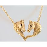 A 14ct yellow gold double horse head pendant with gem set eyes on a ditto chain, 8 grams