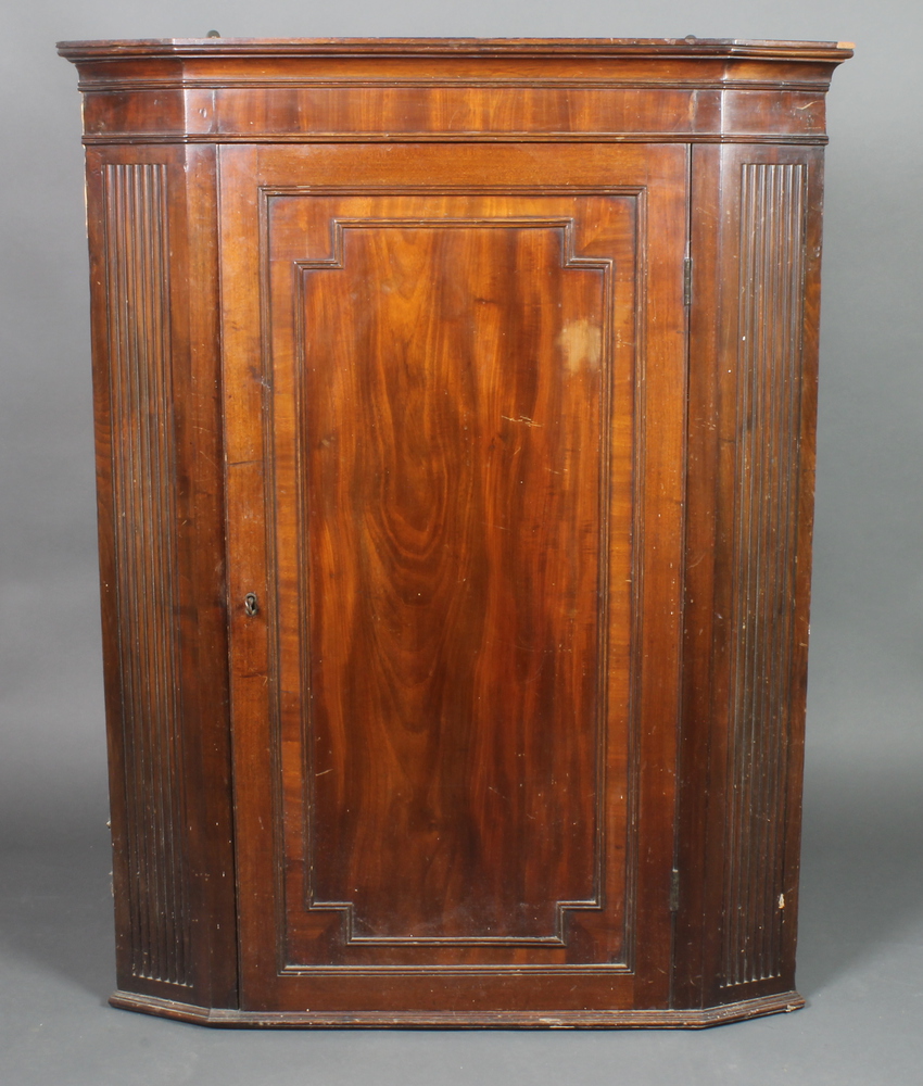 A Georgian mahogany hanging corner cabinet with moulded cornice, the interior fitted shelves