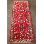 A Persian Qashqai runner with red ground and 7 medallions to the centre 112" x 42"