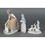 A Nao figure of a girl with goose 8", a ditto of 3 geese 5" and a Lladro figure of a girl holding