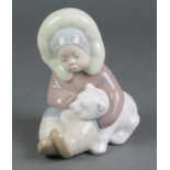 A Lladro figure of a seated Eskimo child holding a polar bear cub 5"