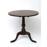 A 19thC oak circular tilt tip table standing on a triform base. 28" diameter  CONDITION: Please Note