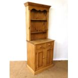 An unusual contemporary narrow stripped pine dresser with open plate rack on a 2 drawer base with