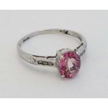 A white gold ring set with central pink sapphire flanked by 3 diamonds to each shoulder