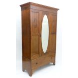 An Edwardian mahogany double wardrobe with oval bevelled edge mirror to central door with single