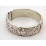 A silver bangle with floral decoration Hallmarked Birmingham 1971 maker H.S Ltd and Marked '