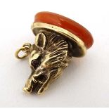 A gilt metal fob seal formed as a boars head with red stone eyes and set with carnelian seal under