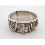 An Indian white metal cuff bangle bracelet  formed as 6 hinged sections each depicting Indian