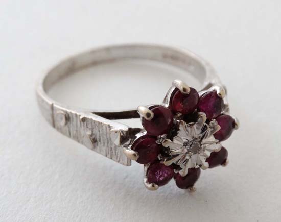 An 18ct white gold ring set with central diamond bordered by 8 rubies  CONDITION: Please Note -