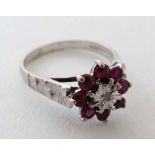 An 18ct white gold ring set with central diamond bordered by 8 rubies  CONDITION: Please Note -