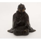 A Chinese patinated cast bronze model of a kneeling religious figure ( monk)  wearing a patterned