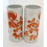 A pair of famille-rose Chinese hand painted porcelain cylinder vases depicting foo dogs in a coral