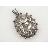 A white metal locket of oval form with decoration to one side depicting an Indian deity. Approx 2
