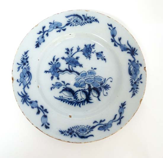 An 18thC Delft plate painted in blue with Chinoiserie floral design with trailing foliate sprays