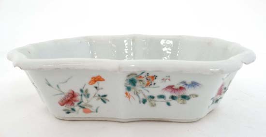 An Oriental shaped dish with hand painted enameled decoration depicting various flowers and