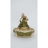 A Royal Dux Bohemia porcelain figural dish modelled as a girl collecting flowers beside a pool .