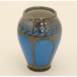 A small baluster shaped vase having resist blue glazed arched panels and a trail of stylised