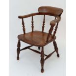 A Victorian elm smoker's bow chair having turned spindle supports and legs and shaped stretchers