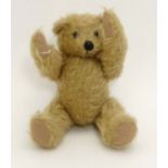 A small golden mohair Teddy bear with jointed limbs and neck, felt pads, stitched nose and mouth and