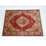 Carpet / rug : a Kum carpet with red ground , central biege medallion having foliate decoration,