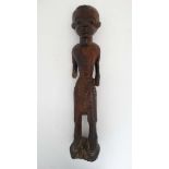 A Native Tribal African carved heavy wooden figure of a male holding a manilla armlet, 23 3/4"