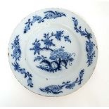 An 18thC Delft plate painted in blue with Chinoiserie floral design with trailing foliate sprays