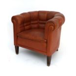 A 20thC Art Deco style leather club chair with button back upholstery and standing on squared