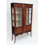 An Edwardian mahogany display case having twin glazed doors before four shelves with swag and bow