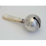 A white metal rattle with mother of pearl teether 3 1/2" long  CONDITION: Please Note -  we do not