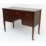 An early 20thC walnut dressing chest / writing table with one central drawer flanked by 2 short