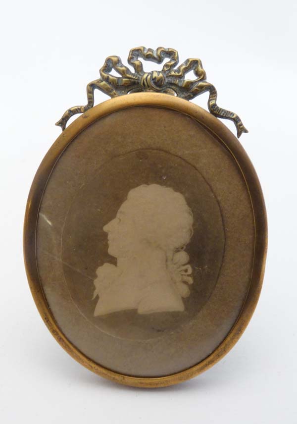 An early 19thC brass miniature easel frame with ribbon cresting  having a Georgian silhouette of a