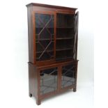 An astral glazed front bookcase with adjustable shelves to top section with dental cornice and