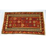 Carpet / rug :   A Kilim rug  eith burgundy ground, green, red, mustardorange and black colours . 90