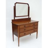 An early 20thC mahogany dressing table having a shaped bevel edged mirror over two short legs and