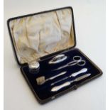 A cased silver mounted manicure set comprising  nail buffer, nail file, scissors, pot, nail brush