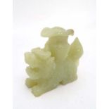 A Chinese jadeite candle holder in the form of a lotus like flower on the back of a temple dog 4"