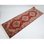 Carpet / rug : a red ground Kum Runner  with beige, mustard and black colours, 82 1/2" x 27 9/